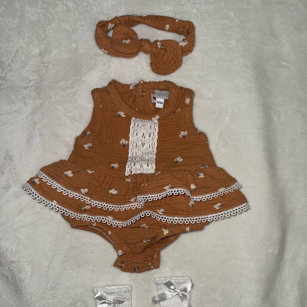 Rachel Zoe Tan Baby Romper with White Details paired with long white socks.